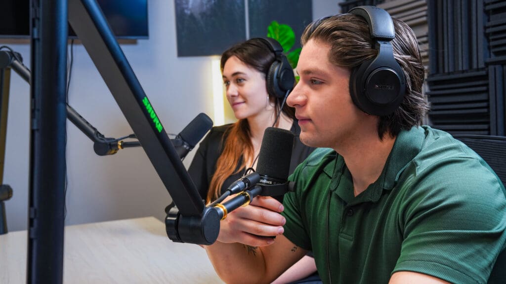 Two podcast guests, a man and a woman speaking into microphones